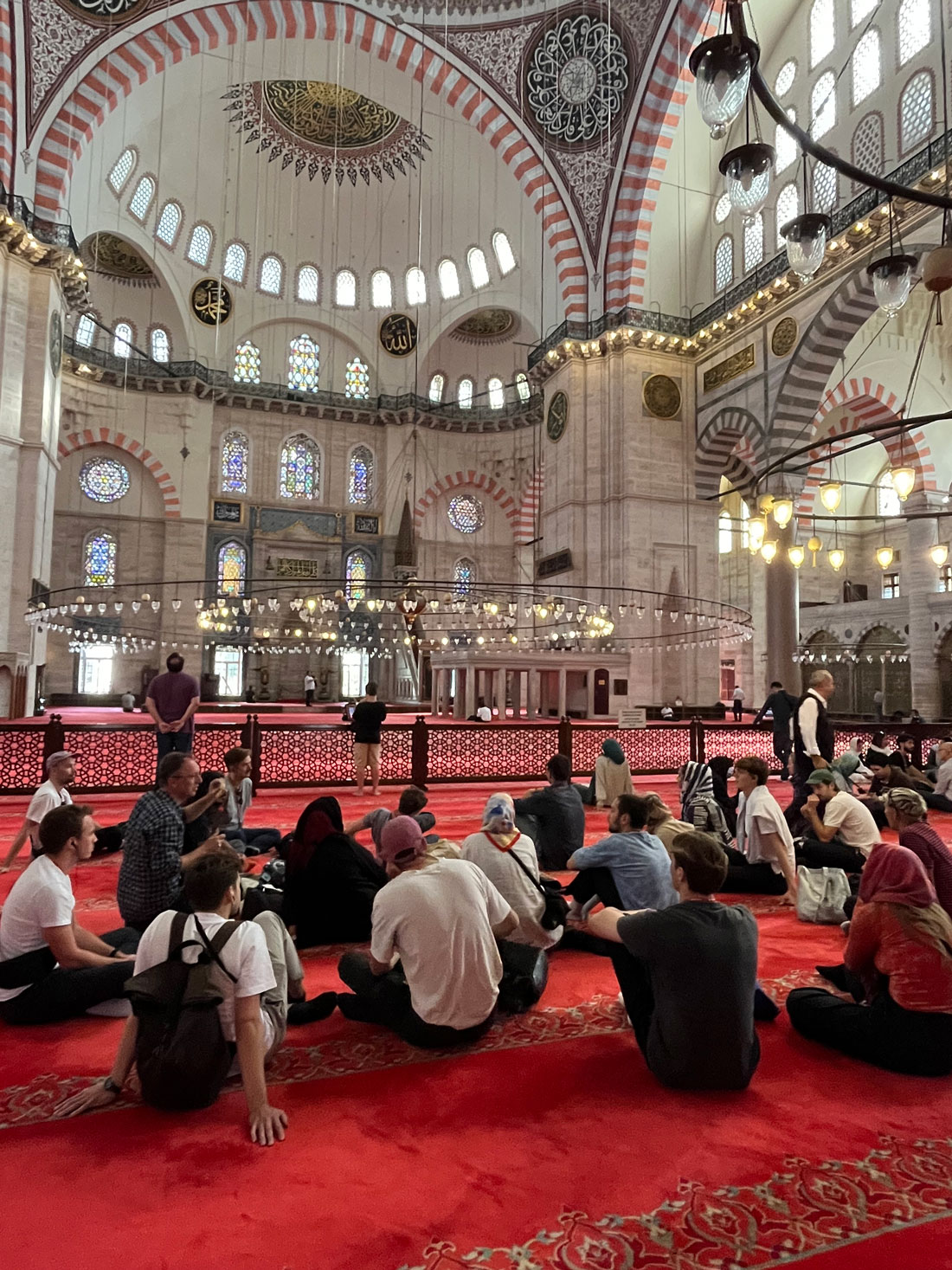 Menschen setzen sich auf einem roten Teppich auf dem Boden in einer Moschee in Istanbul, Türkei. Oktober 2023